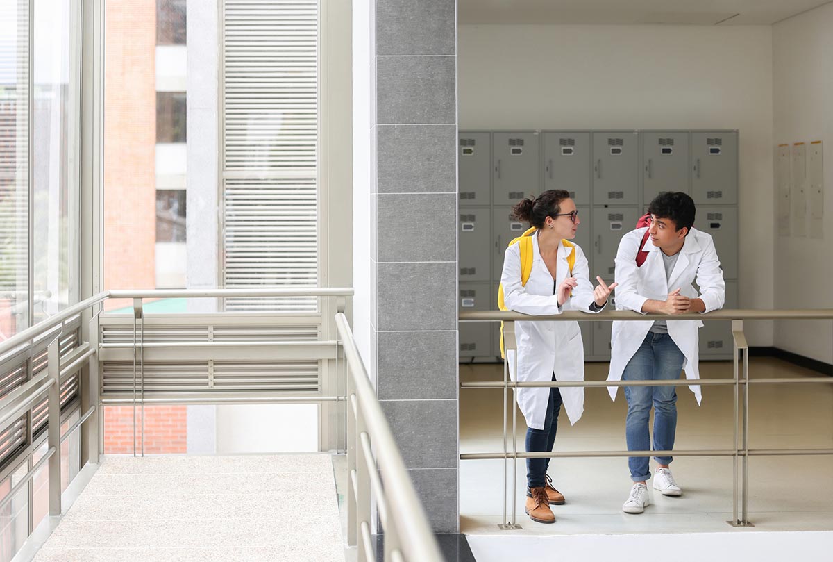 Two students chatting wearing white lab coats